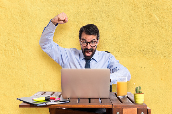 Exited man with laptop on desk